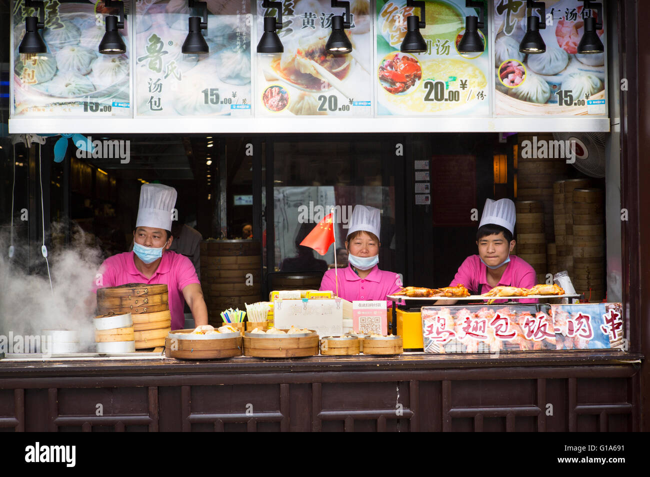 Chinesische Köche mit Gesichtsmasken gegen die Verunreinigung der Luft, die an eine Straße in Nanjing, China Stockfoto