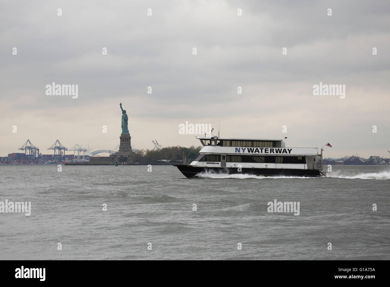 Ein NY Waterway Boot führt vorbei an der Freiheitsstatue im Hafen von New York City, USA. Stockfoto
