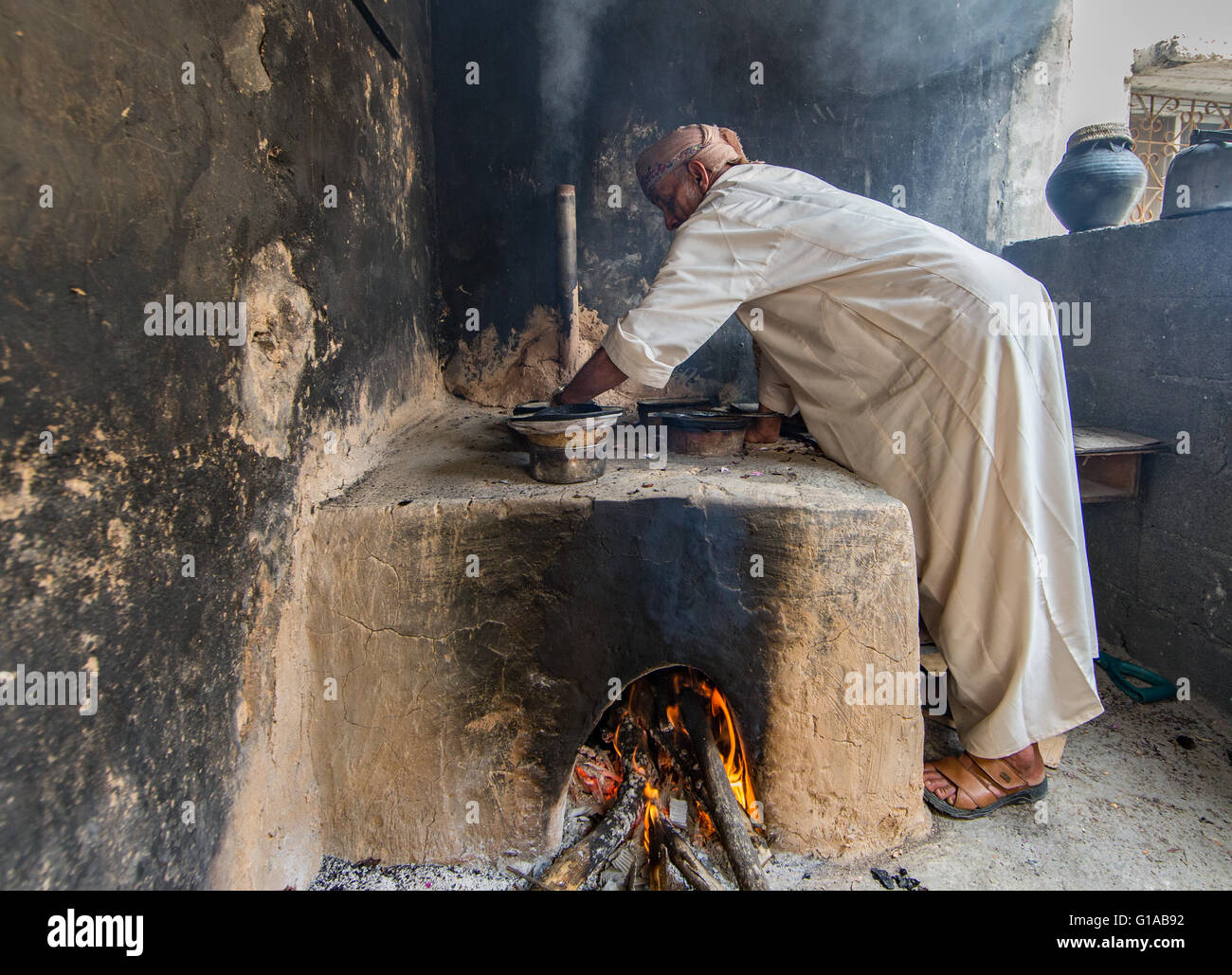 Jabal Al Akhdar, Oman - April 2016: Ein Greis omanischen ist Rosenwasser aus Rosenblättern mit traditionellem Ofen extrahieren Stockfoto