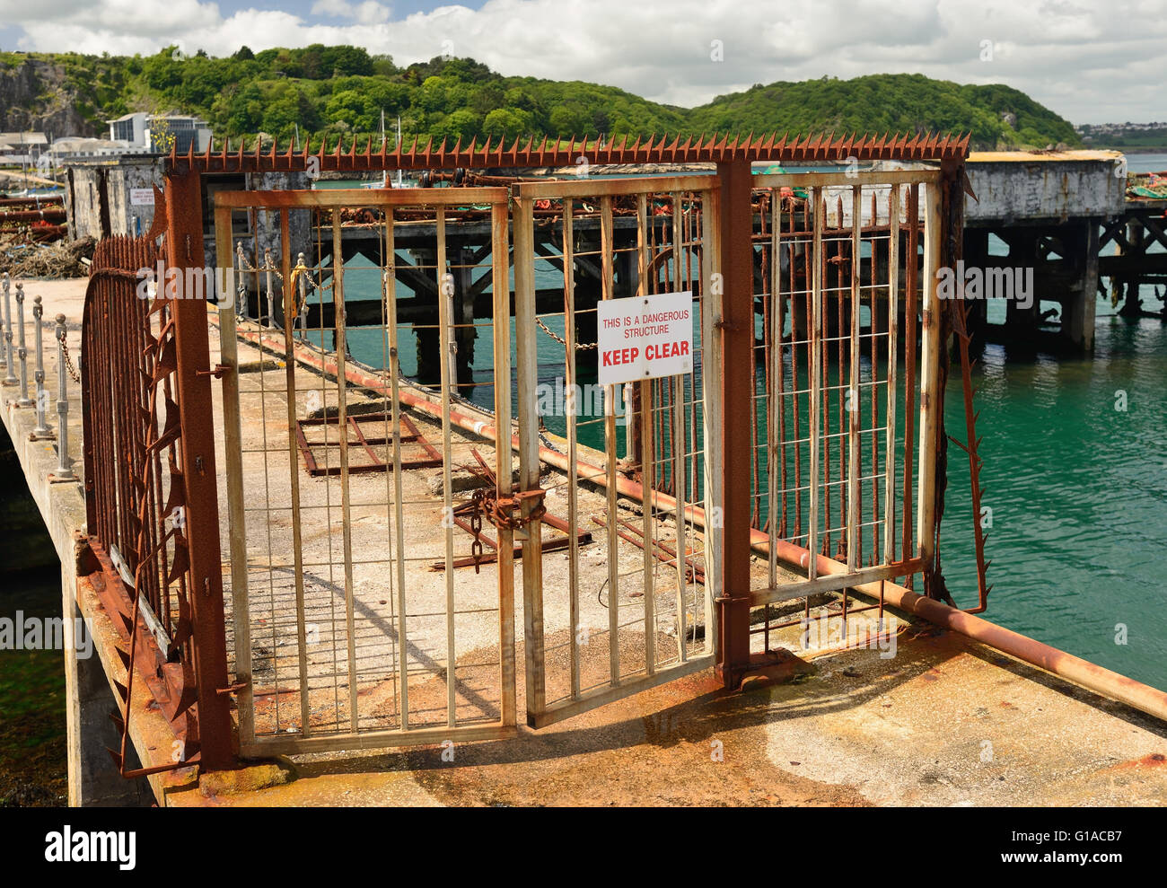 Rusty Tore und Zäune rund um eine gefährliche Struktur - eine alte verlassene Mole im Hafen von Brixham. Stockfoto