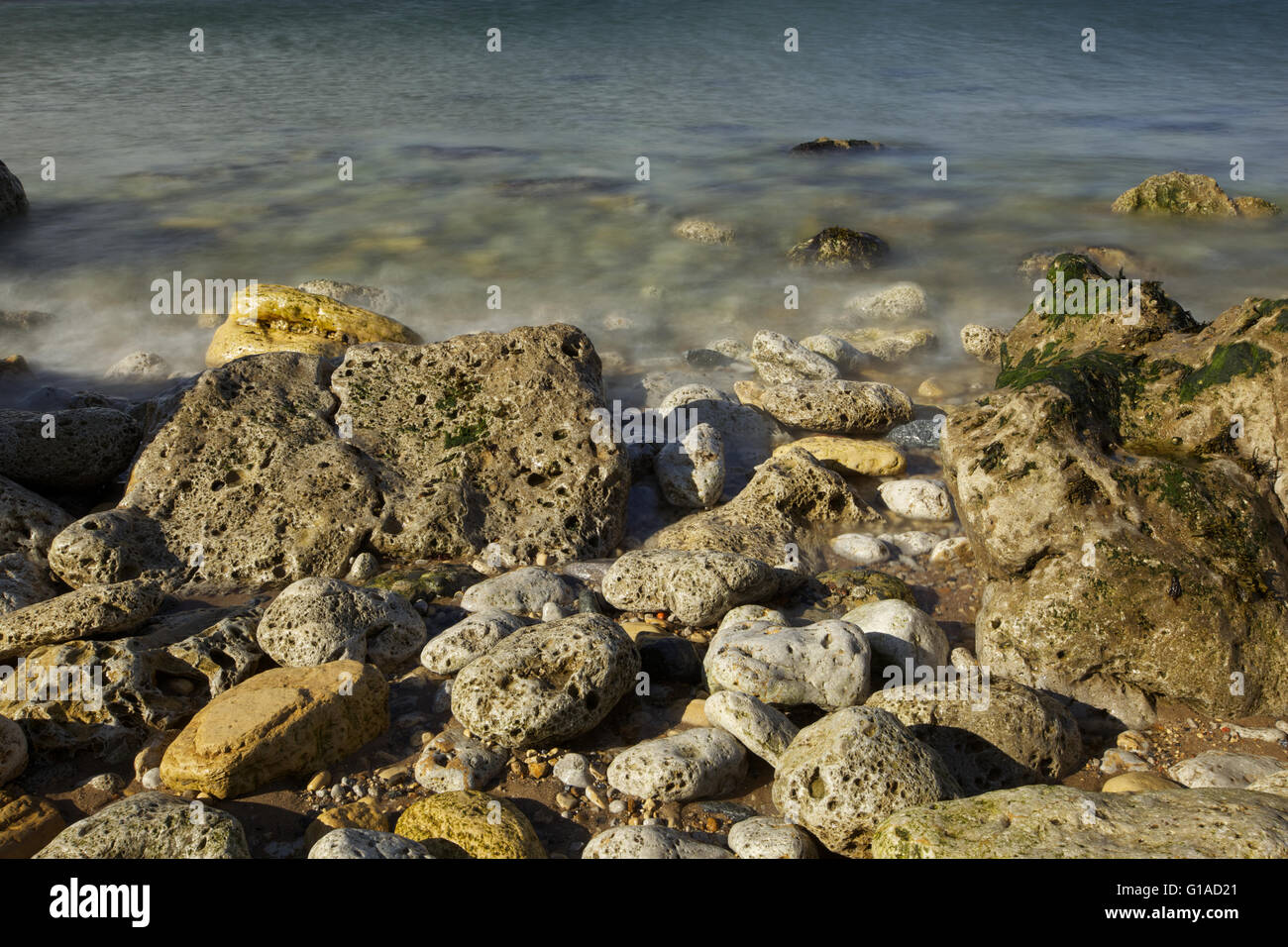 Meeresküste mit Steinen, Wellen in Zeitlupe Stockfoto