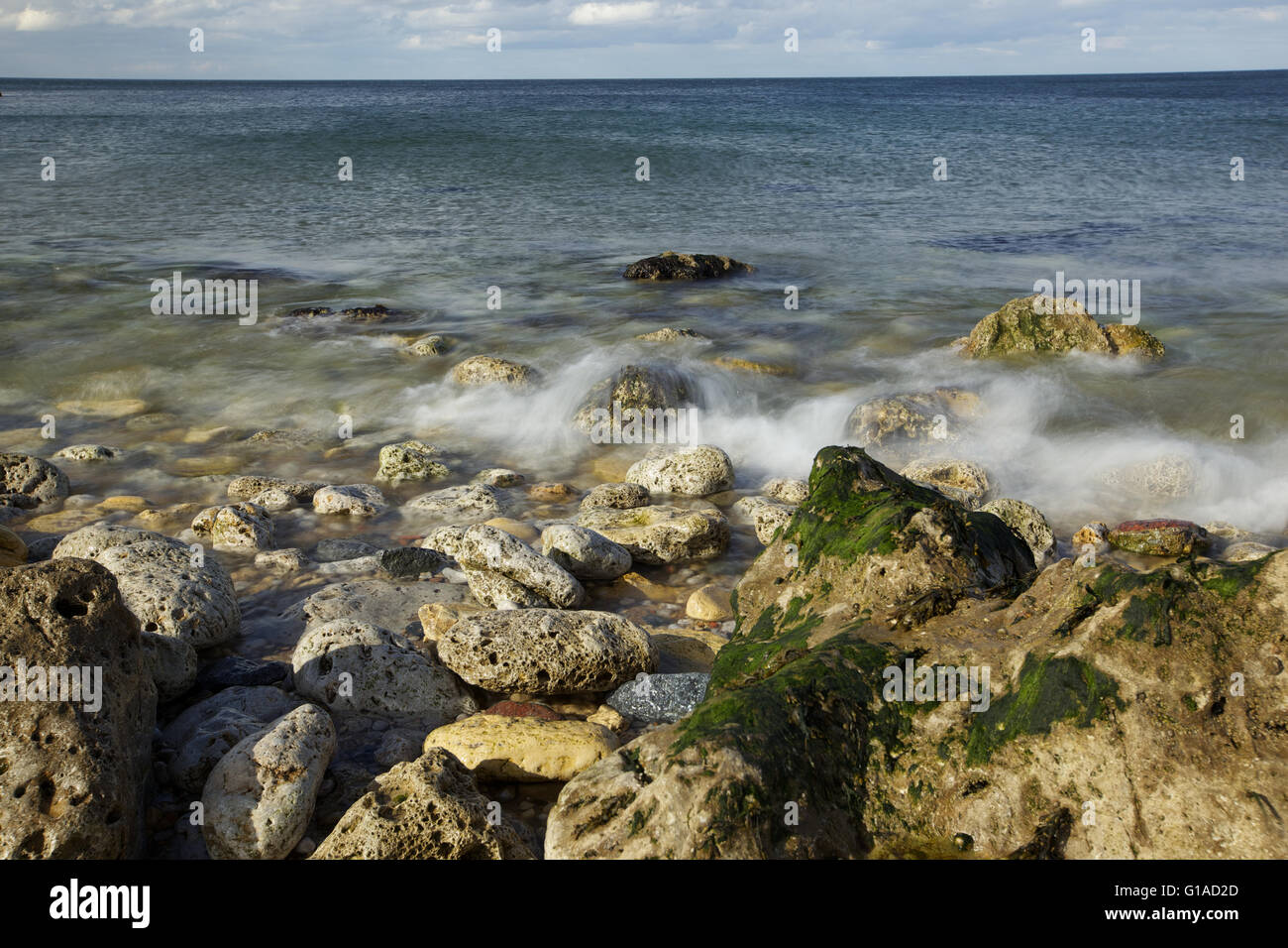 Meeresküste mit Steinen, Wellen in Zeitlupe Stockfoto