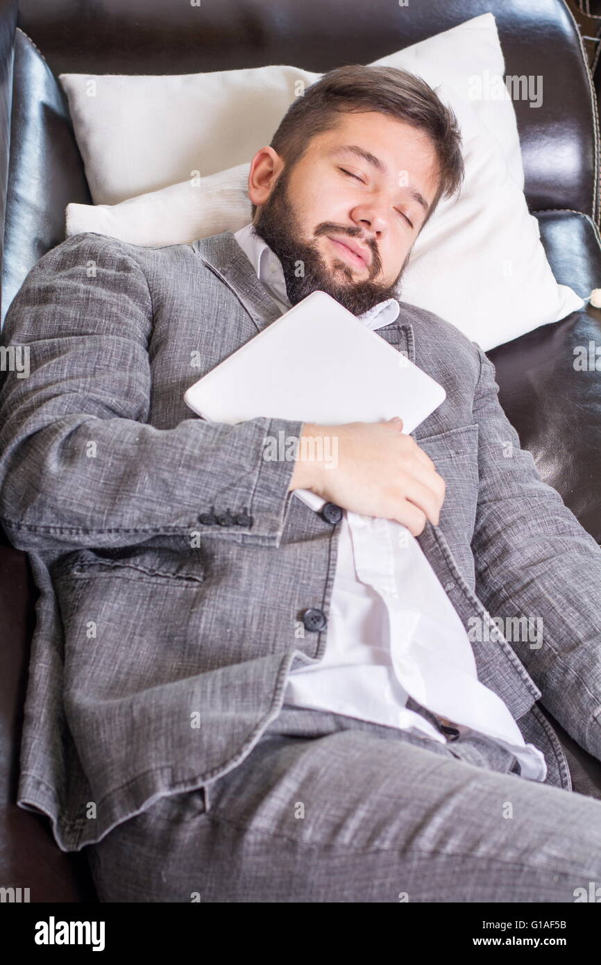 Verschlafene Geschäftsmann mit einem Tablet-Gerät auf einem sofa Stockfoto