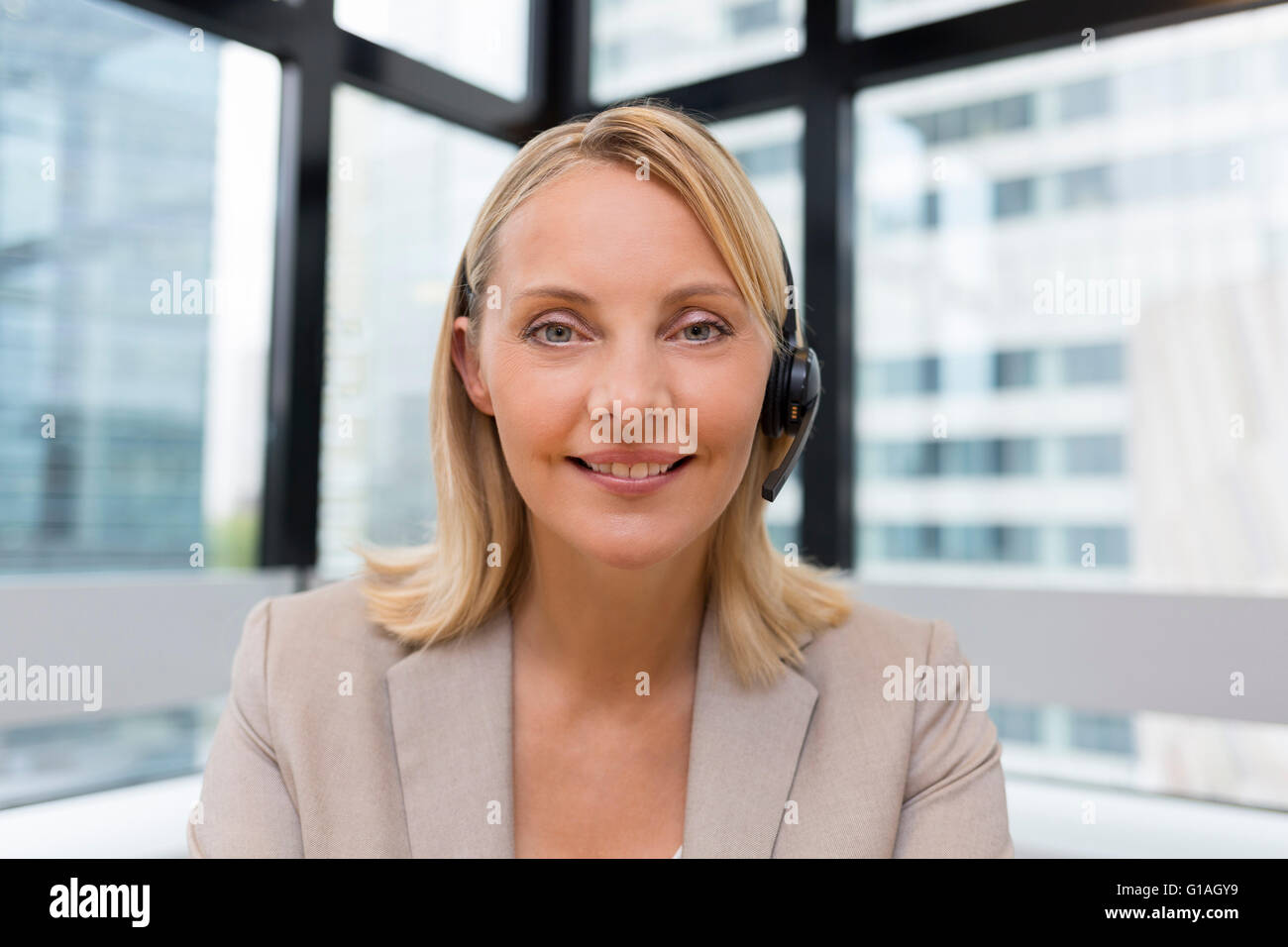 Lächelnde Geschäftsfrau im Büro auf Videokonferenz, Kopfhörer, Sicht Stockfoto