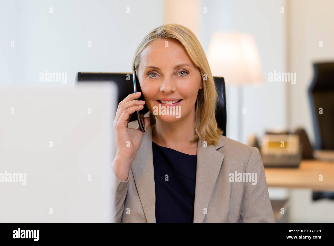 Fröhliche Geschäftsfrau auf Smartphone im Büro. Blick in die Kamera Stockfoto