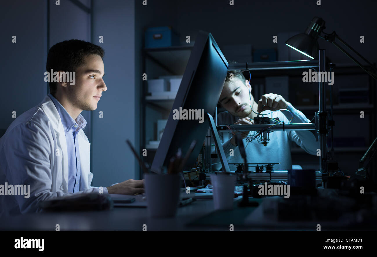 Engineering-Team arbeitet im Labor in der Nacht, ein Student arbeitet mit einem Computer und die ander ist die Anpassung eines 3D-Druckers Stockfoto