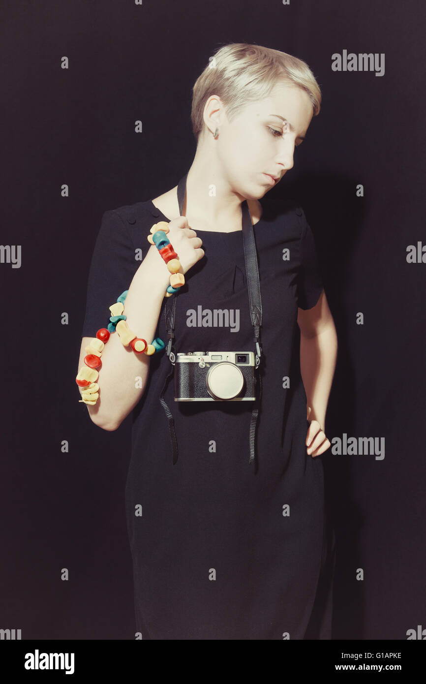 Porträt der jungen Frau mit Kamera auf schwarzem Hintergrund Stockfoto