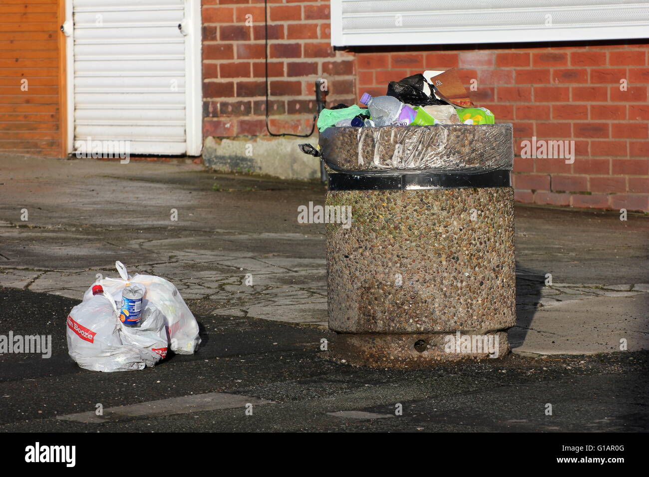 Bin in einer Seitenstraße in einem Vorort von Stockport - Müll über fließenden öffentlichen volle Säcke mit Müll neben den Mülleimer Links sind Stockfoto