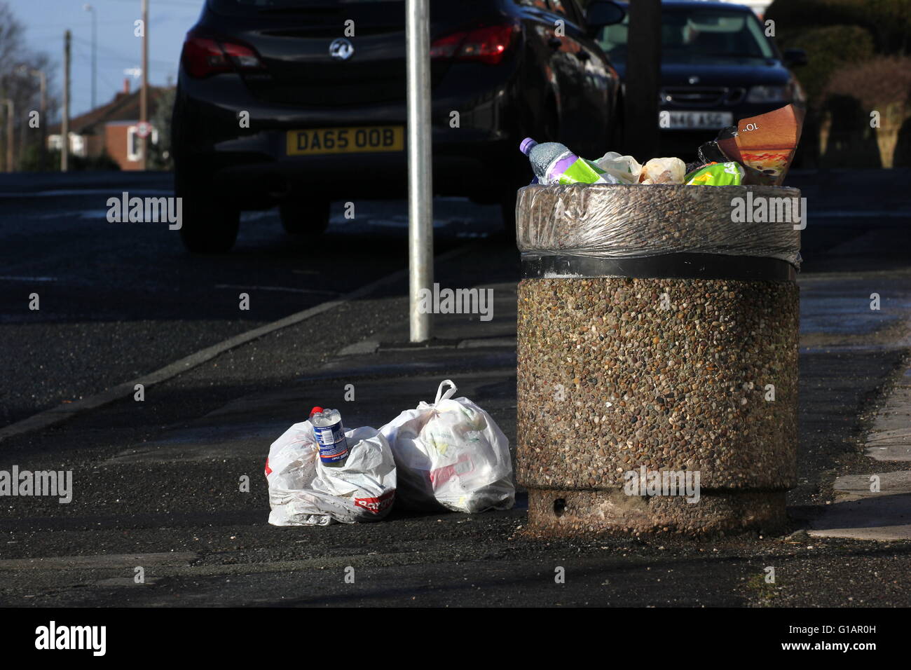 Bin in einer Seitenstraße in einem Vorort von Stockport - Müll über fließenden öffentlichen volle Säcke mit Müll neben den Mülleimer Links sind Stockfoto