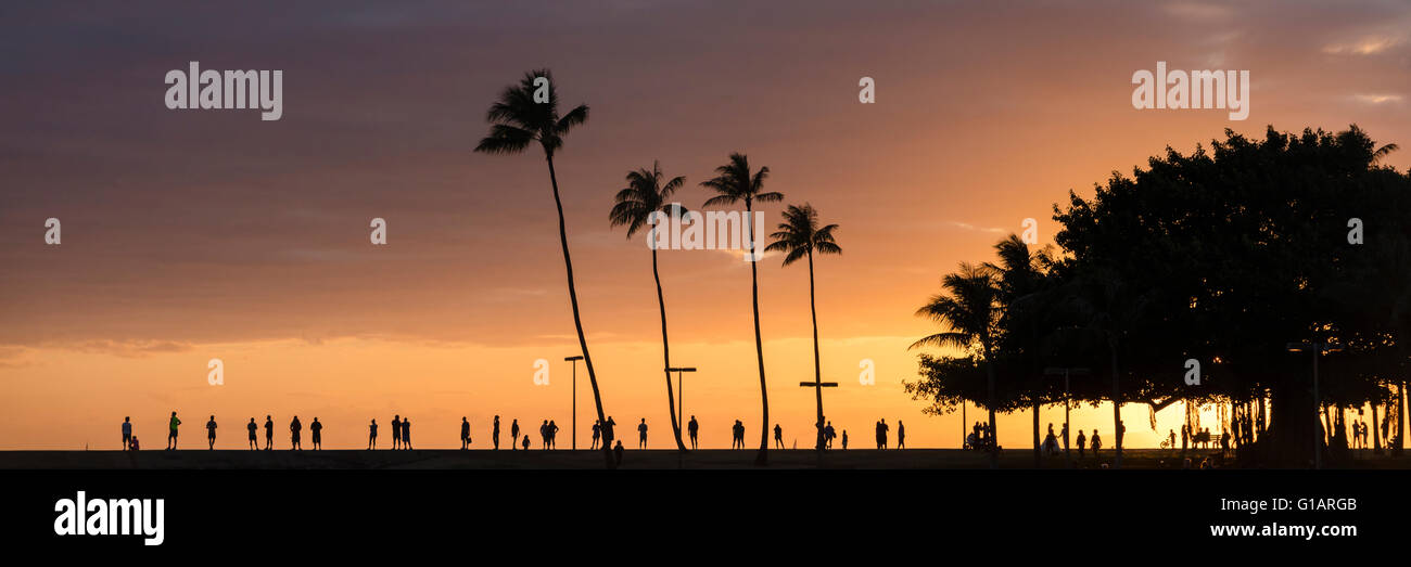 Touristen, die den Sonnenuntergang am Ala Moana beach Park in Honolulu, Oahu. Stockfoto