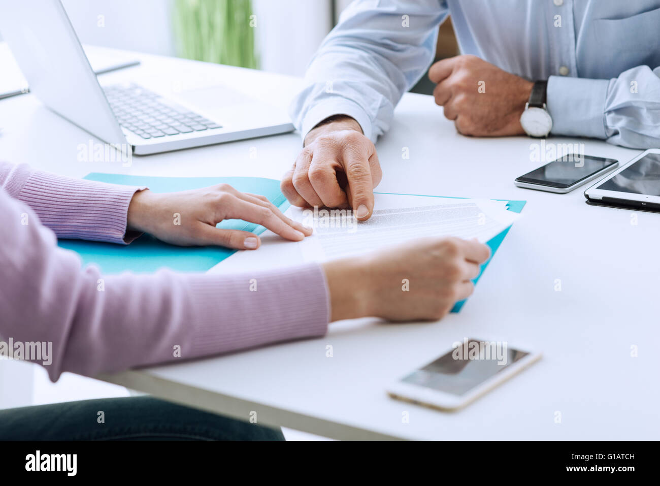 Junge Frau mit einem Geschäft treffen mit Führungskraft in seinem Büro, er zeigt auf einen Vertrag und Erklärungen Stockfoto