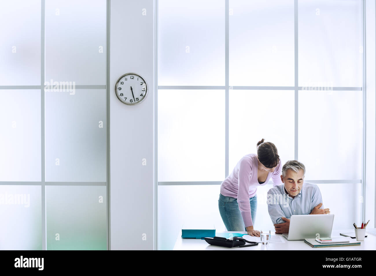 Executive mit seiner Assistentin am Schreibtisch arbeiten, sie sind benutze ein Laptop und Internetverbindung Stockfoto