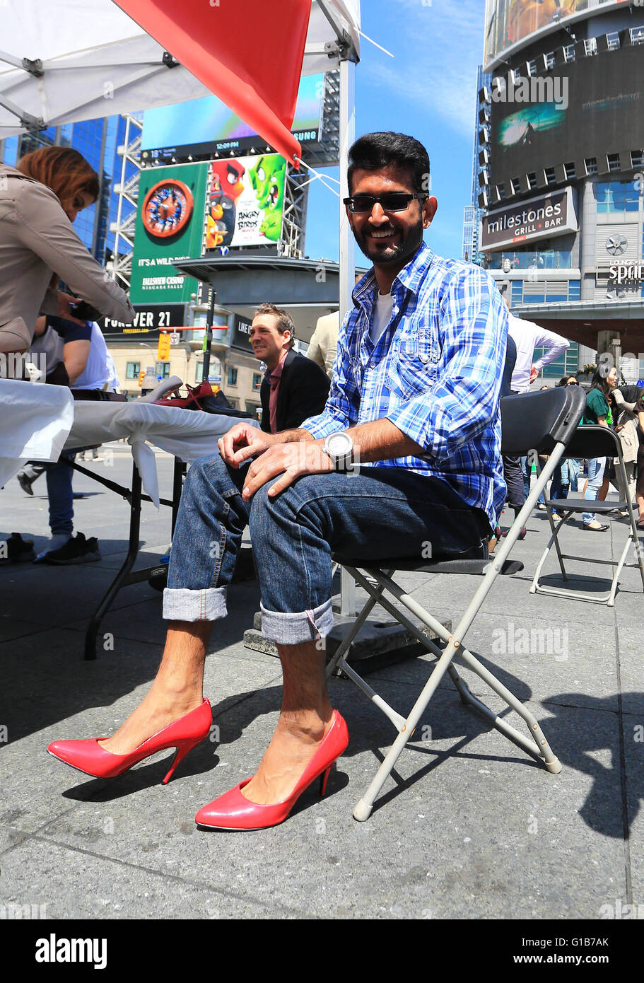 Toronto, Kanada. 12. Mai 2016. Ein Mann bekommt seine hochhackigen Schuhe  bereit während der 7. jährlichen Walk A Mile In Her Shoes-Veranstaltung am  Yonge-Dundas Square in Toronto, Kanada, 12. Mai 2016. Die