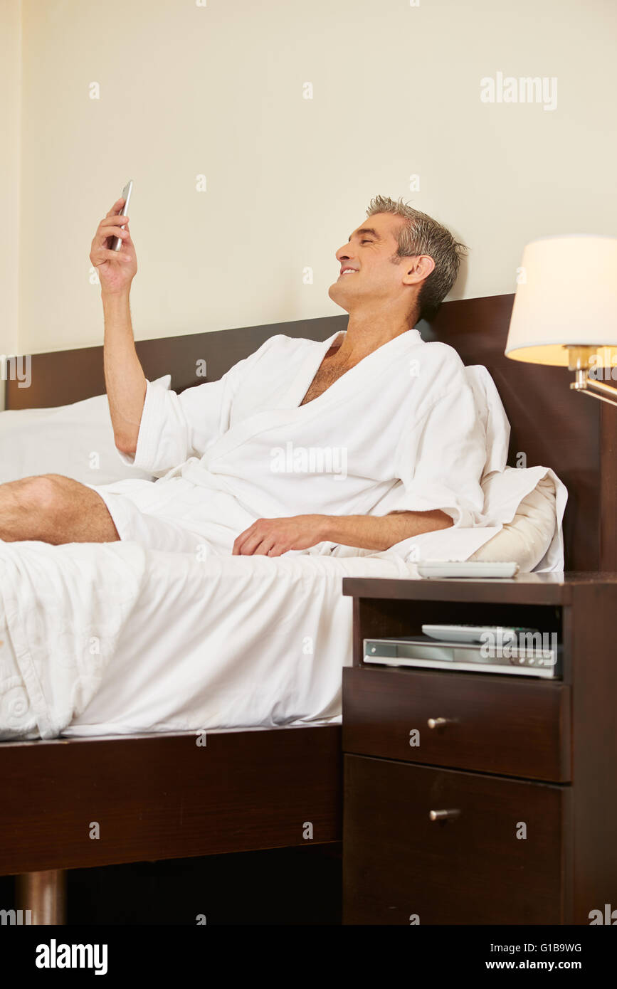 Mann im Hotelzimmer lesen SMS auf seinem smartphone Stockfoto