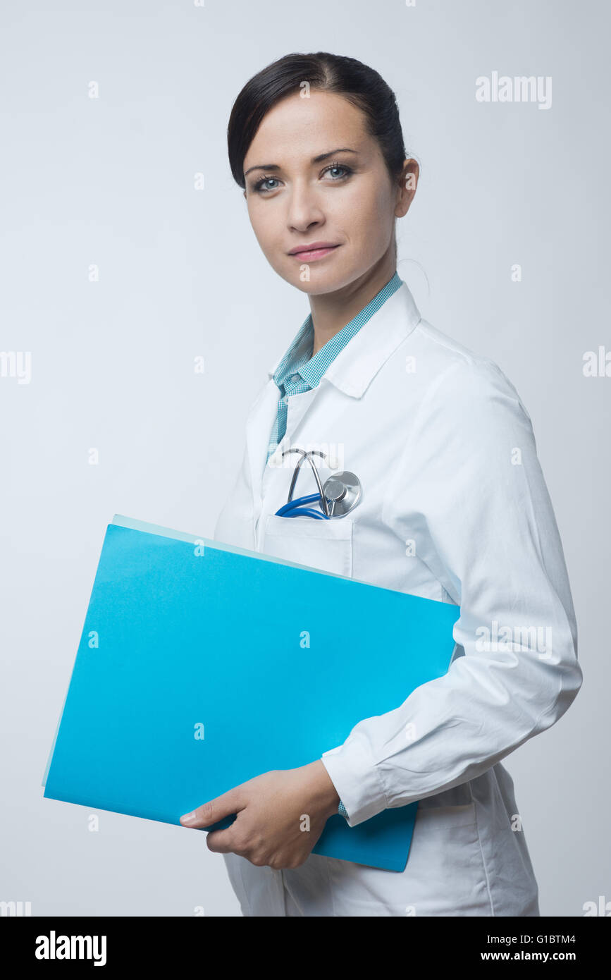 Lächelnde junge Ärztin, die medizinischen Unterlagen Datei. Stockfoto
