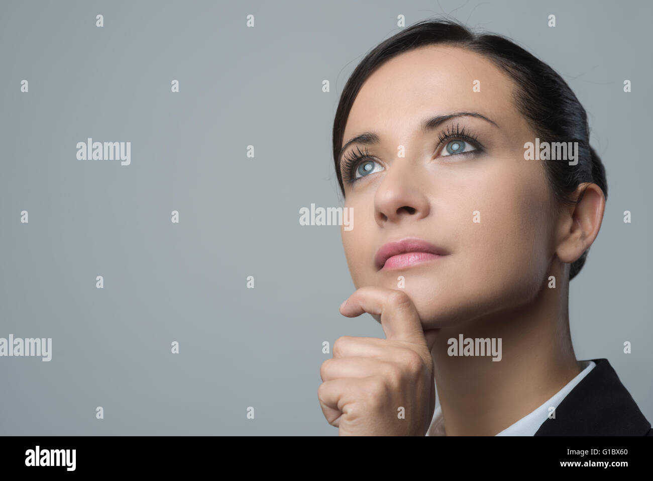 Attraktive nachdenklich Geschäftsfrau mit Hand am Kinn wegsehen. Stockfoto