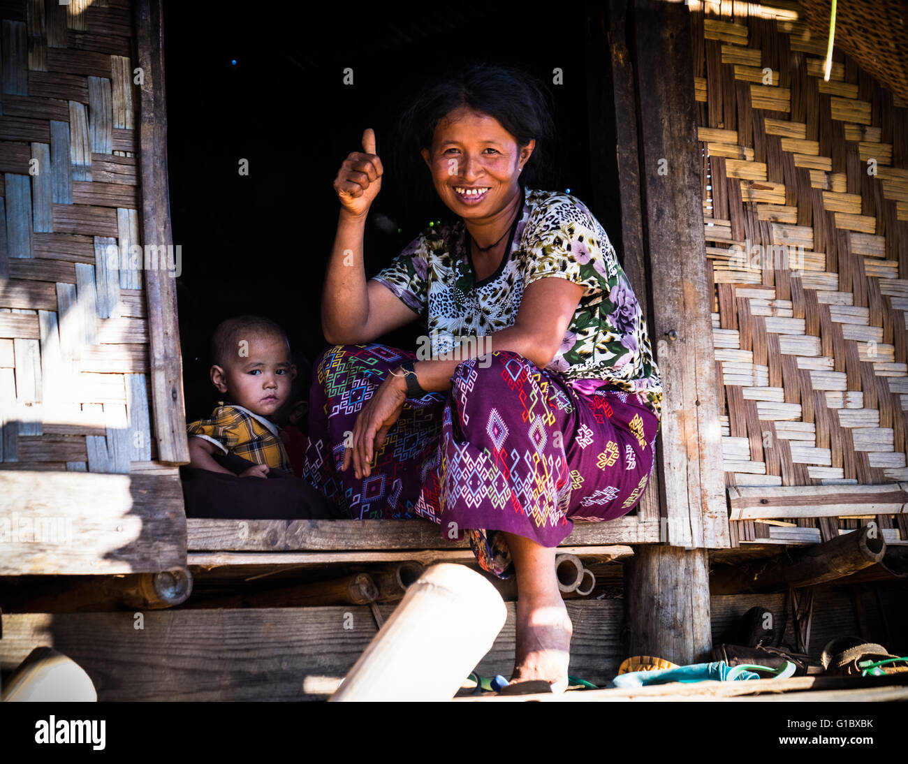 Eine Dame und ein Baby am Eingang zu ihrem Bambushaus in Pankam Dorf in der Nähe von Hsipaw Stockfoto