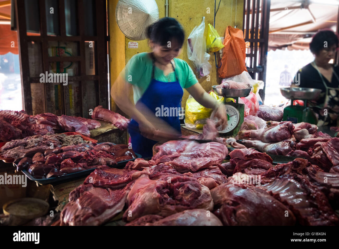 Ein weibliche Metzger, der Zubereitung von Fleisch für einen Kunden in Hoi An Central Market Stockfoto