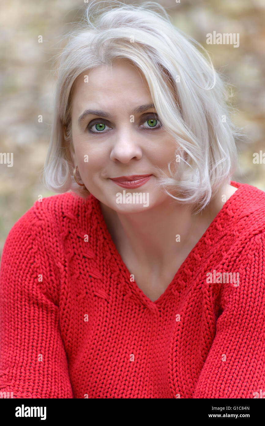 Porträt einer Green-Eyed Blondine im roten Pullover Stockfoto