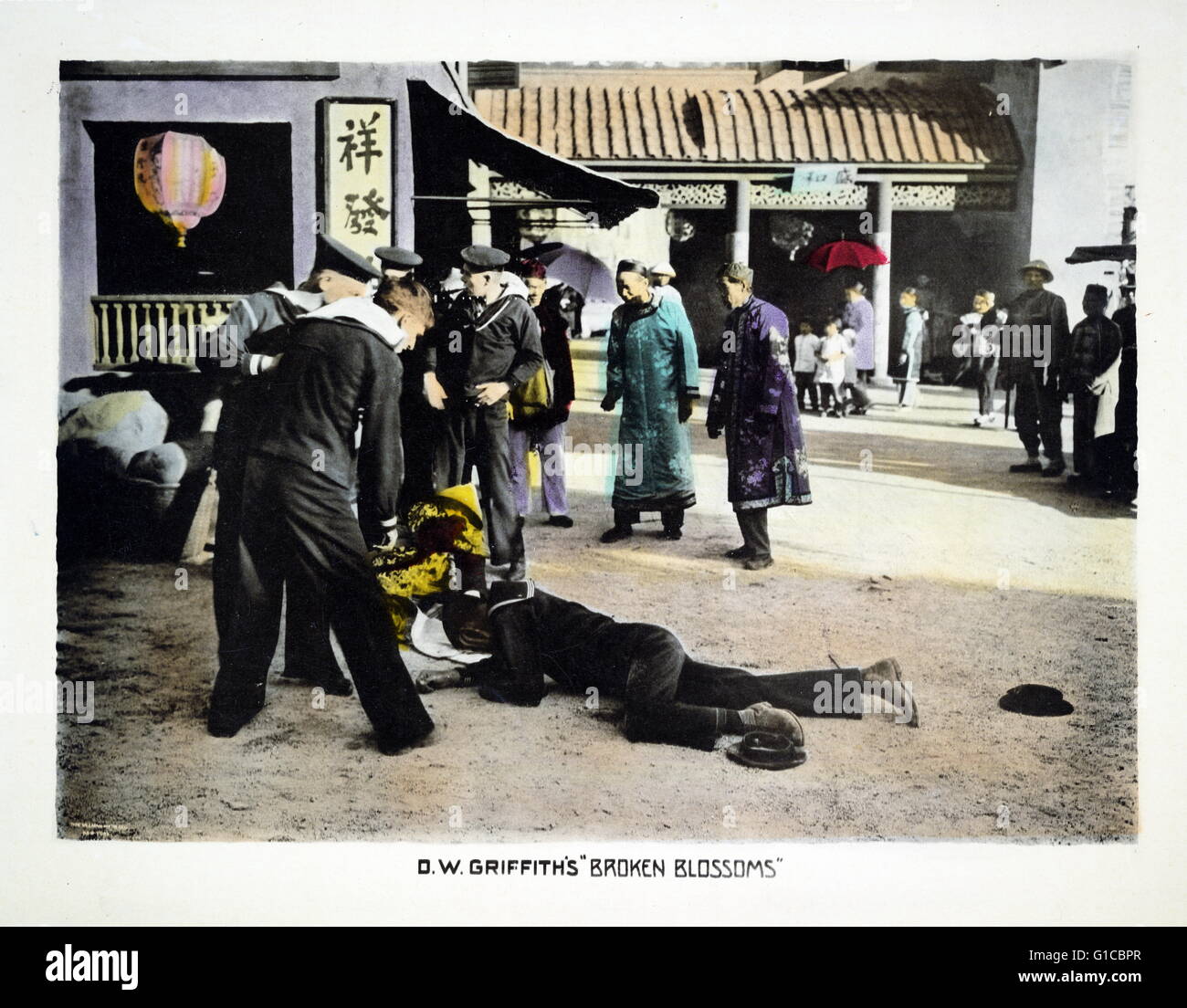 Motion Picture Lobby Card für "Gebrochene Blüten" zeigt Segler stehen über zwei Leichen, ein Chinese und ein Seemann, liegend auf der unbefestigten Straße in Chinatown; Chinesische Bewohner stand zurück und beobachten. Datiert 1919 Stockfoto