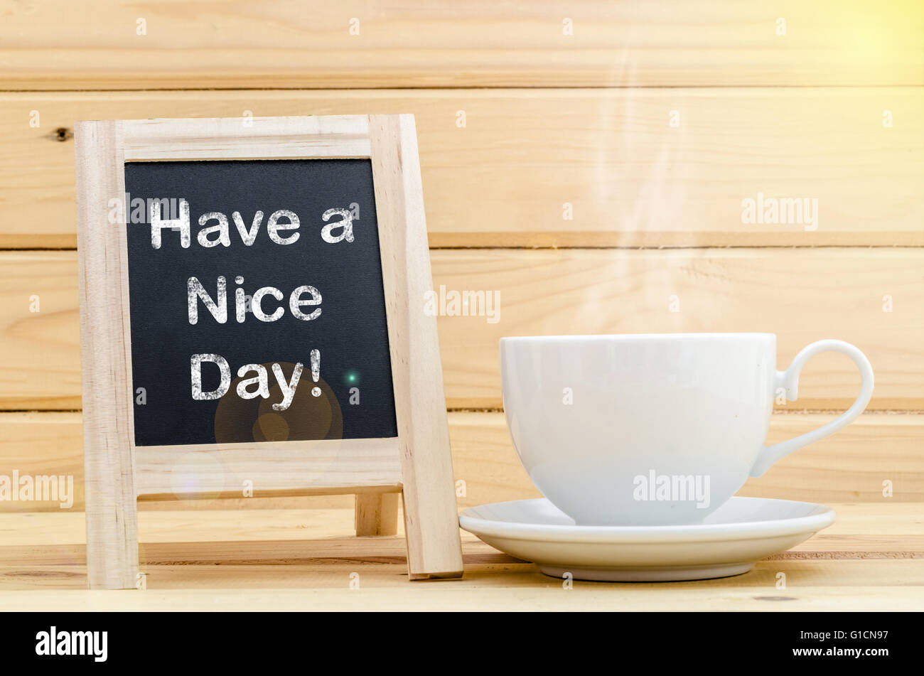 Haben Sie einen schönen Tag Wort auf Tafel und Kaffee in weiße Tasse mit Rauch. Tageslicht. Stockfoto