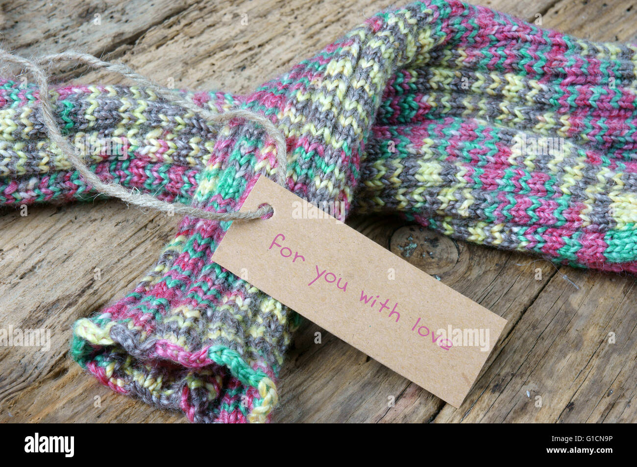 Frauen Hand stricken Wolle Handschuh zu Weihnachtsgeschenk, ein besonderes Geschenk für kalte Winter, bunte Wolle Ball, hölzernen Hintergrund Stockfoto