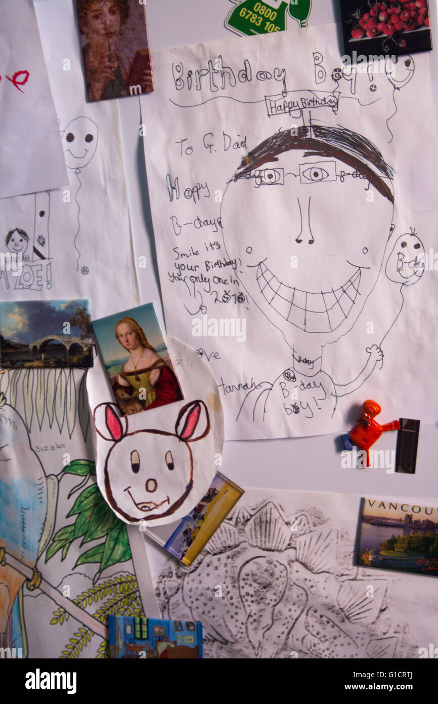 Kinder Zeichnungen von Magneten auf der Kühlschranktür gehalten Stockfoto