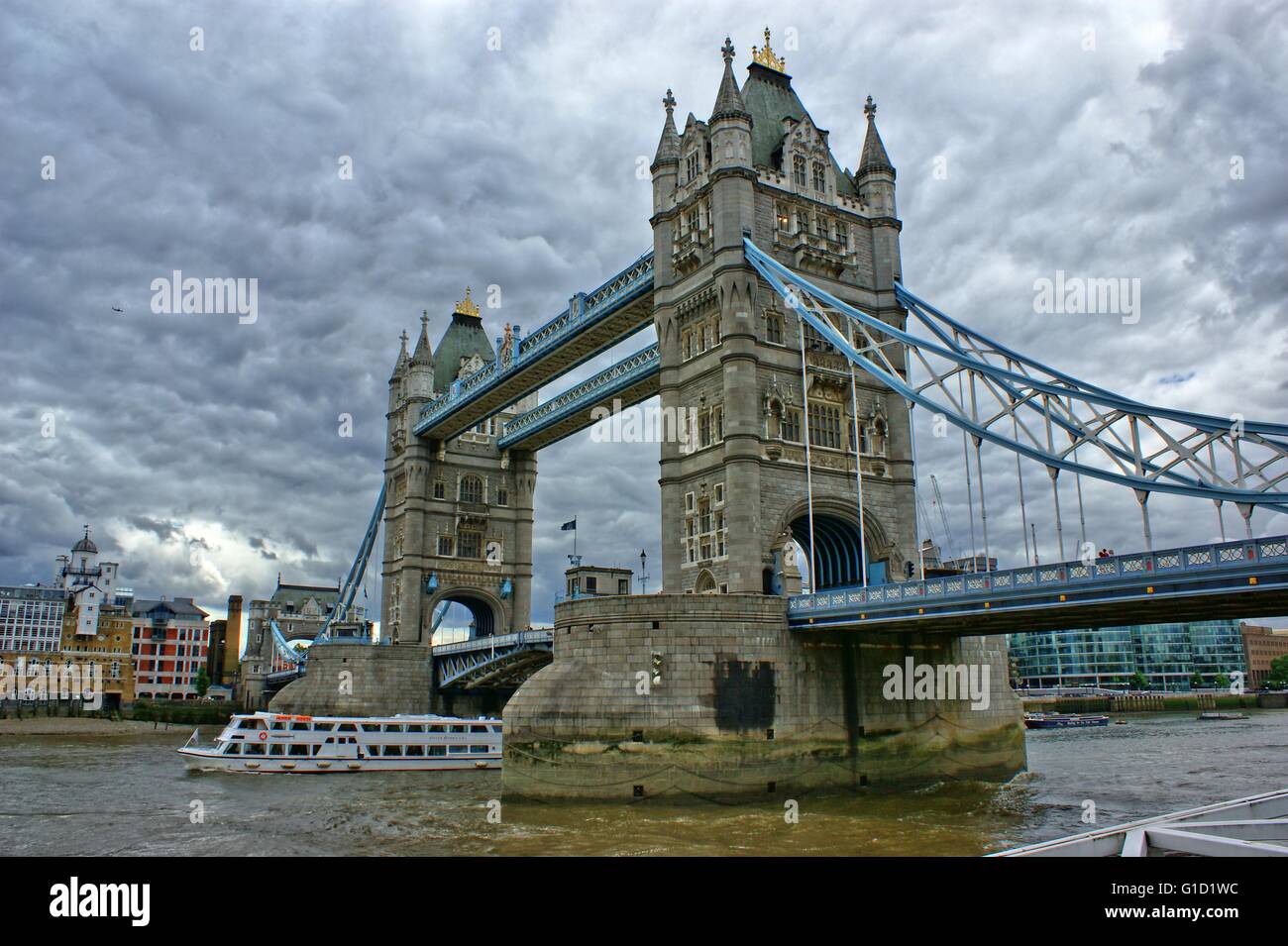 London Bridge, nahe dem Tower of London, dramatischen Blick mit bewölktem Himmel und alten Steinmauern Stockfoto