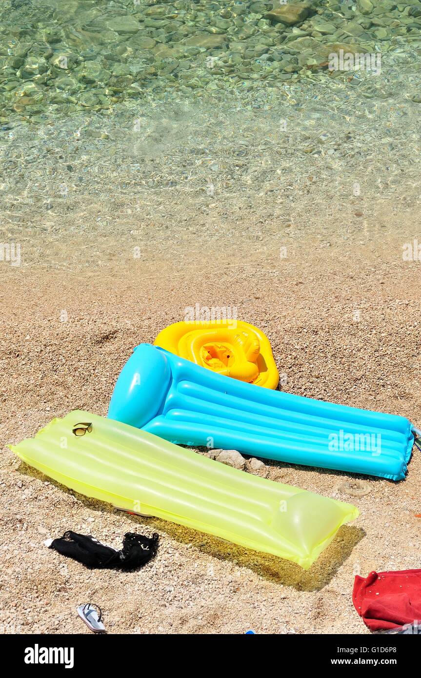 Bunte schwebende Betten mit Strandzubehör in Kieselstrand Stockfoto