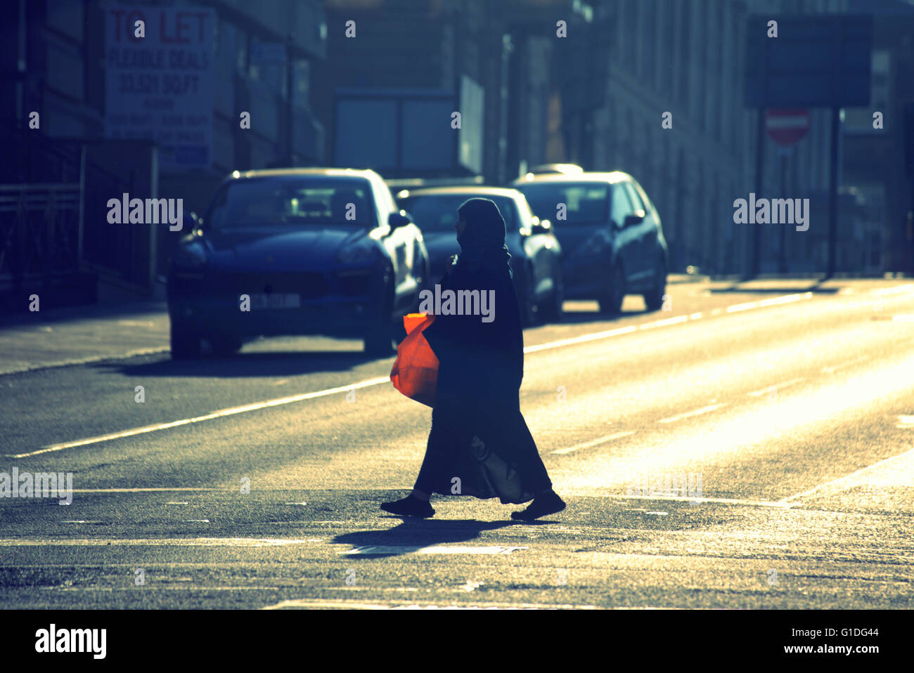 Silhouette der Asiatin mit rote Tasche auf Glasgow Straße mit Straße Contre-Jour hinterleuchtete in Glasgow, Schottland, Großbritannien. Stockfoto