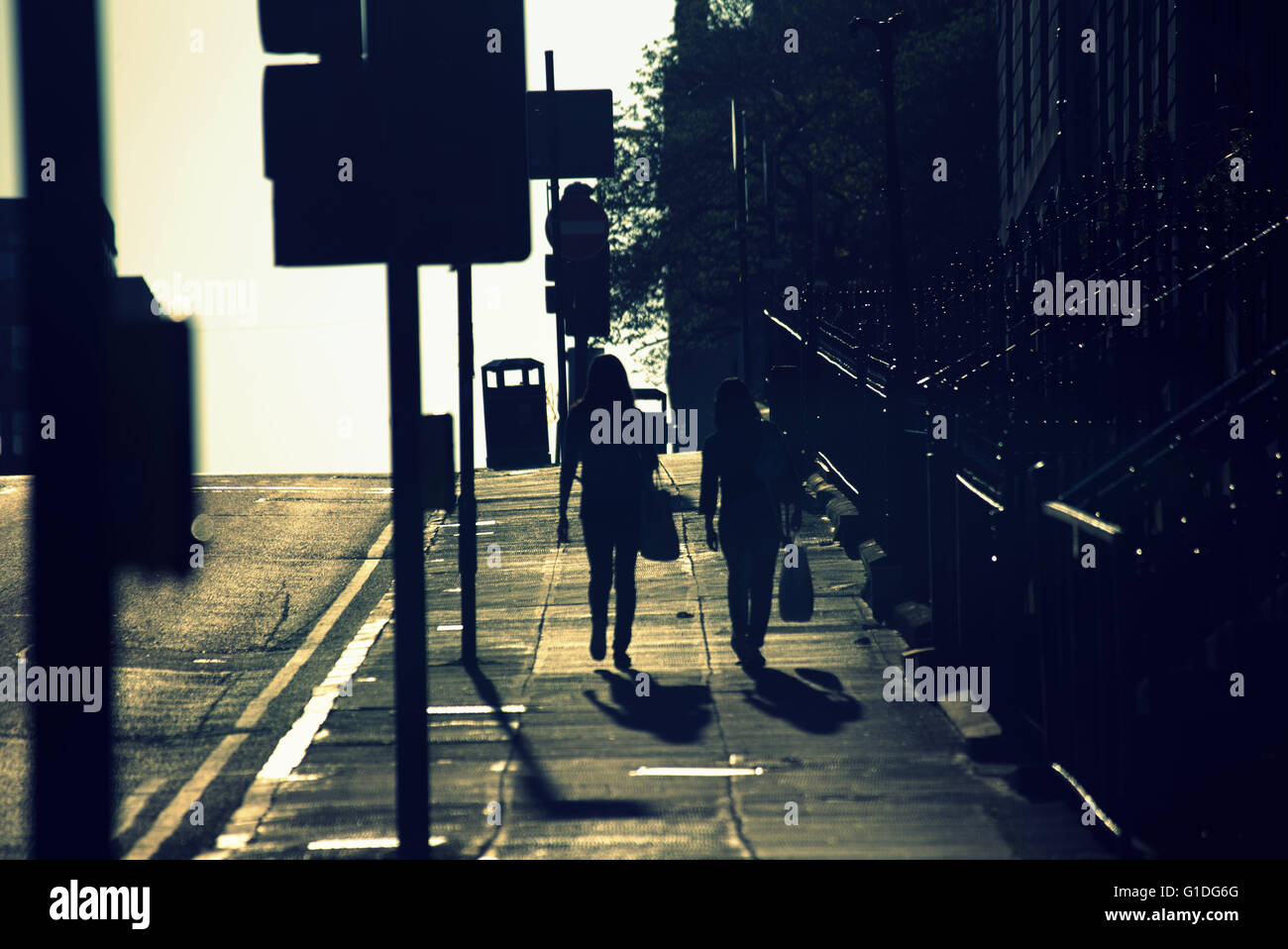 Silhouette von zwei Frauen mit Taschen auf Glasgow Straße mit Straße Contre-Jour hinterleuchtete in Glasgow, Schottland, Großbritannien. Stockfoto