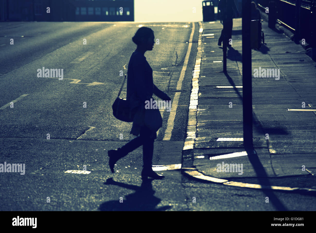 Silhouette der jungen Frau, die in Glasgow Straße mit Straße Contre-Jour damenhaft hinterleuchtete in Glasgow, Schottland, Großbritannien. Stockfoto