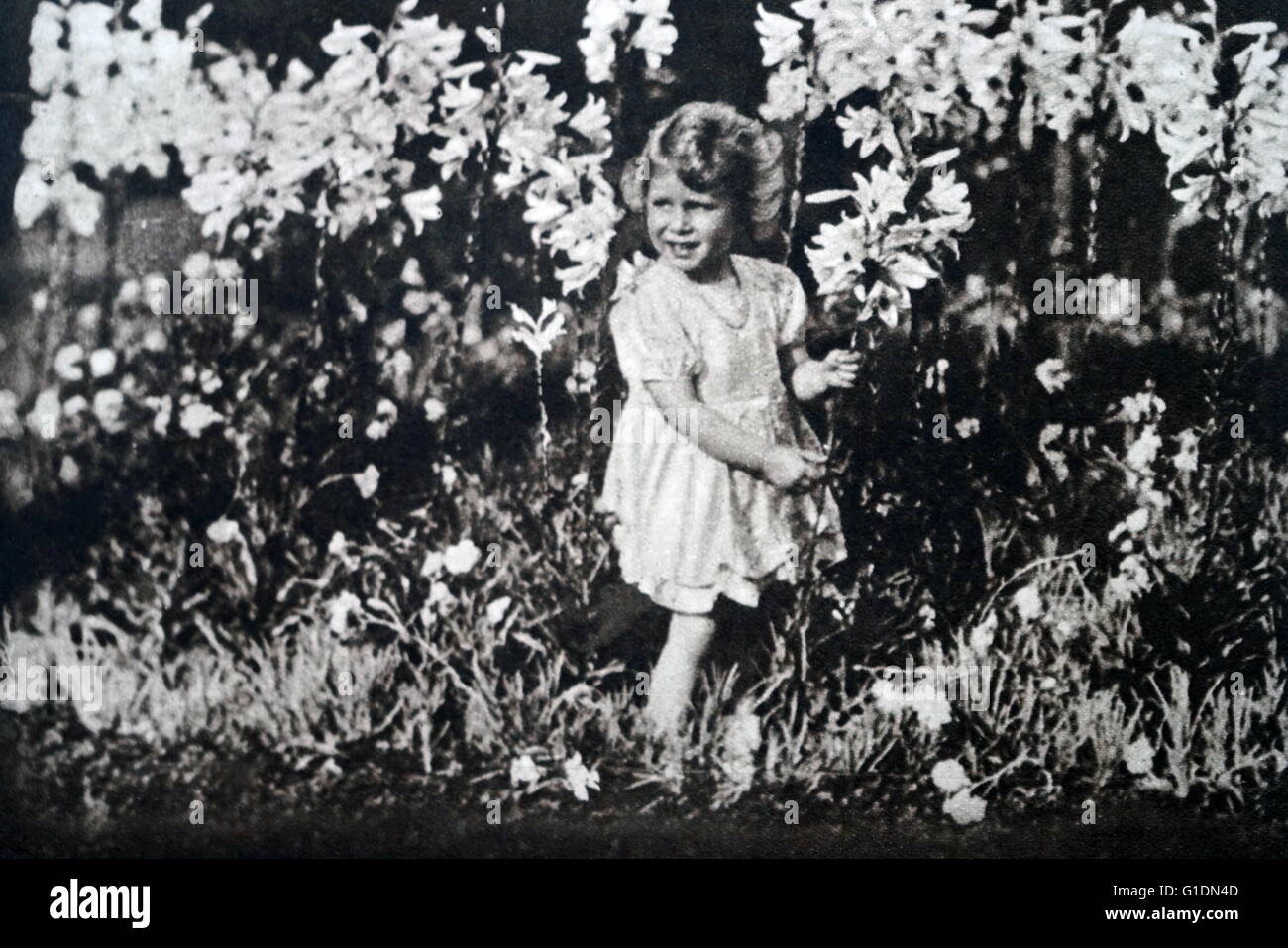 Foto von einer jungen Prinzessin Elizabeth (1926-) die ältere Schwester von Prinzessin Margaret (1930-2002) und zukünftige Königin unter den Blumen spielen. Vom 20. Jahrhundert Stockfoto