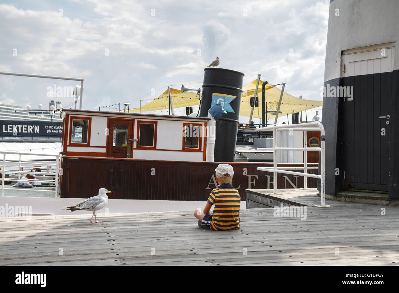 Kind und eine Möwe sitzen und Relaxen vor dem Boot im Hafen von Oslo in Norwegen Stockfoto
