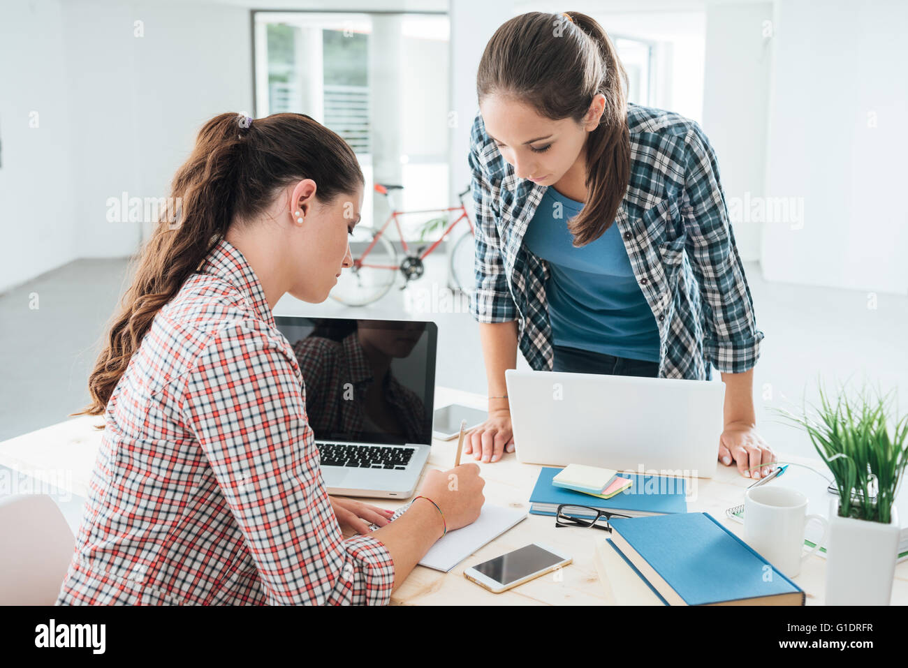 Junge Mädchen mit Laptops zu Hause zu studieren, man hilft ihrer Freundin und überprüfen ihre Hausaufgaben Stockfoto