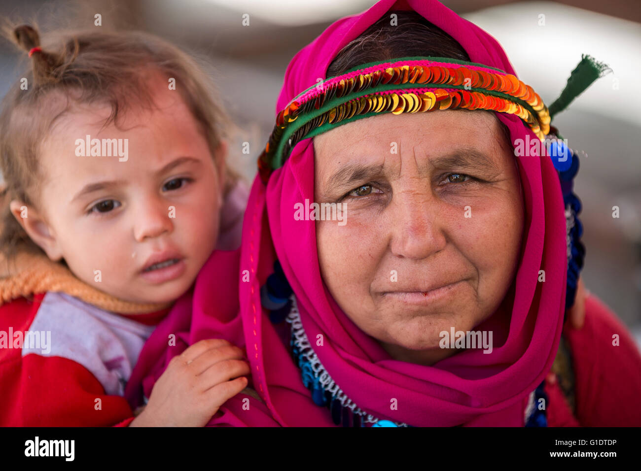 Mutter trägt ihr Baby im lokalen Kopfkleid auf dem Rücken in der Landschaft der Provinz Aydin, Türkei. Stockfoto