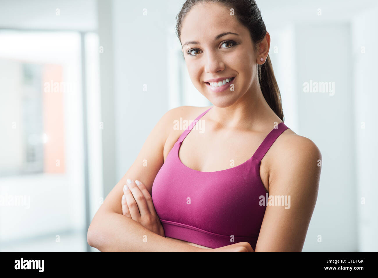 Junge lächelnde Frau posiert in der Turnhalle und Blick auf Kamera, Fitness und gesunden Lifestyle-Konzept Stockfoto