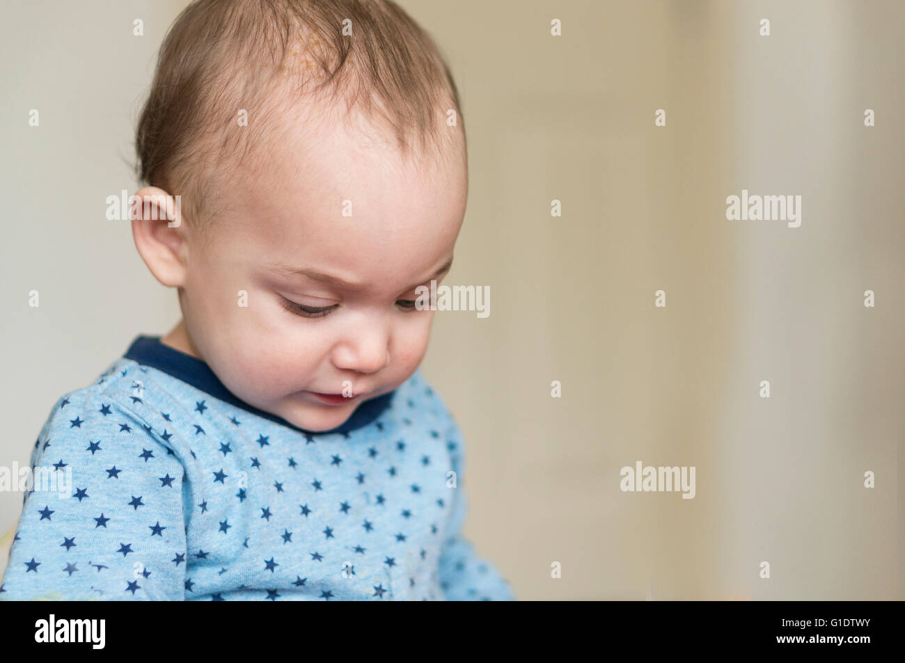 Baby Boy in blau oben blickte auf etwas aus Schuss Stockfoto