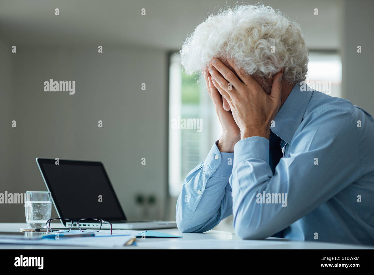 Erschöpften Geschäftsmann mit Kopf in Händen sitzen am Schreibtisch, Störung und Depressionen Bürokonzept Stockfoto