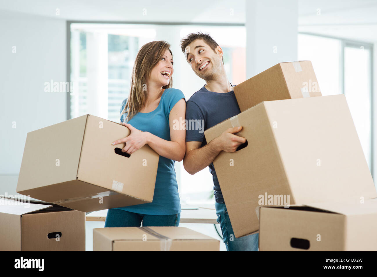 Glückliches Paar einander Augen anstarrte und tragen in ihrem neuen Haus-Boxen Stockfoto