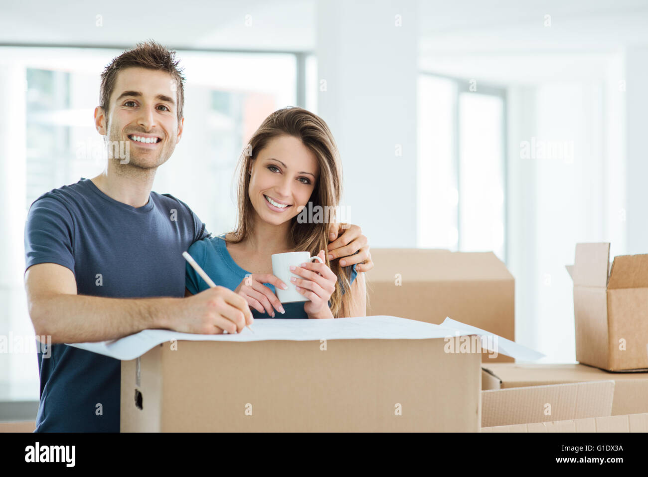 Glückliches Paar planen und entwerfen ihr neue Haus umgeben von Kartons, zieht er an einem Projekt Stockfoto