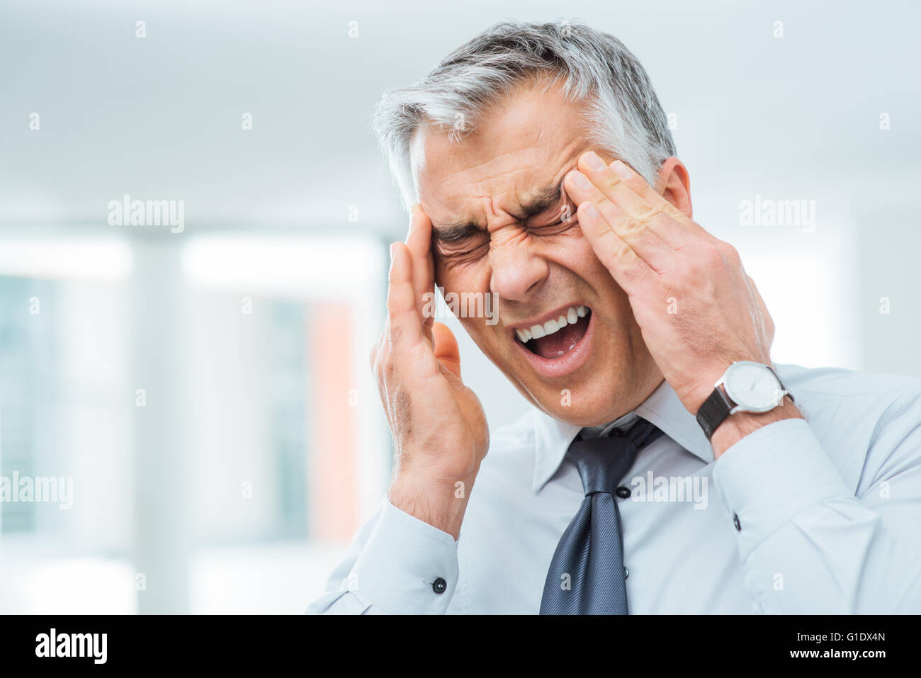 Unternehmer haben eine schreckliche Kopfschmerzen und berühren seine Tempel, Stress und Krankheiten Konzept leiden Stockfoto