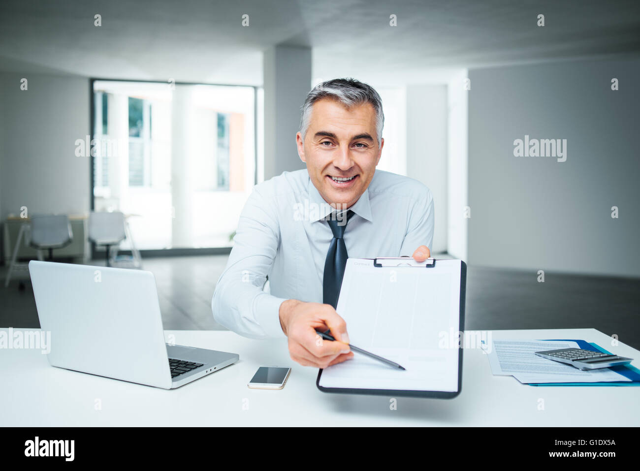 Zuversichtlich Geschäftsmann am Schreibtisch Übergabe einer Zwischenablage und ein Stift, Vertrag Signatur und Vereinbarung Konzept Stockfoto