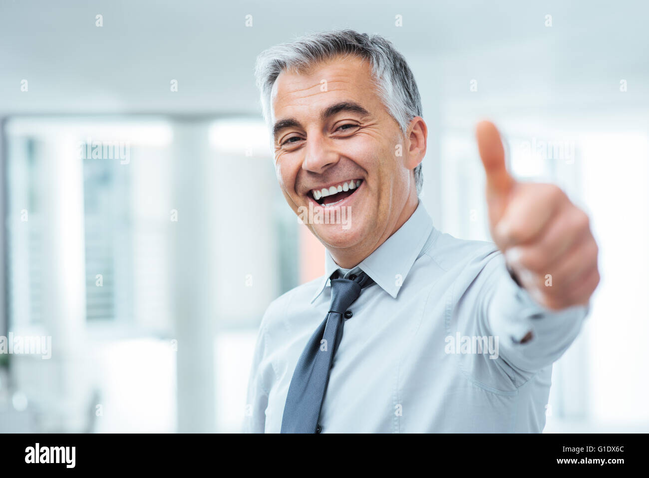 Fröhliche Geschäftsmann Daumen hoch posieren und lächelt in die Kamera Stockfoto