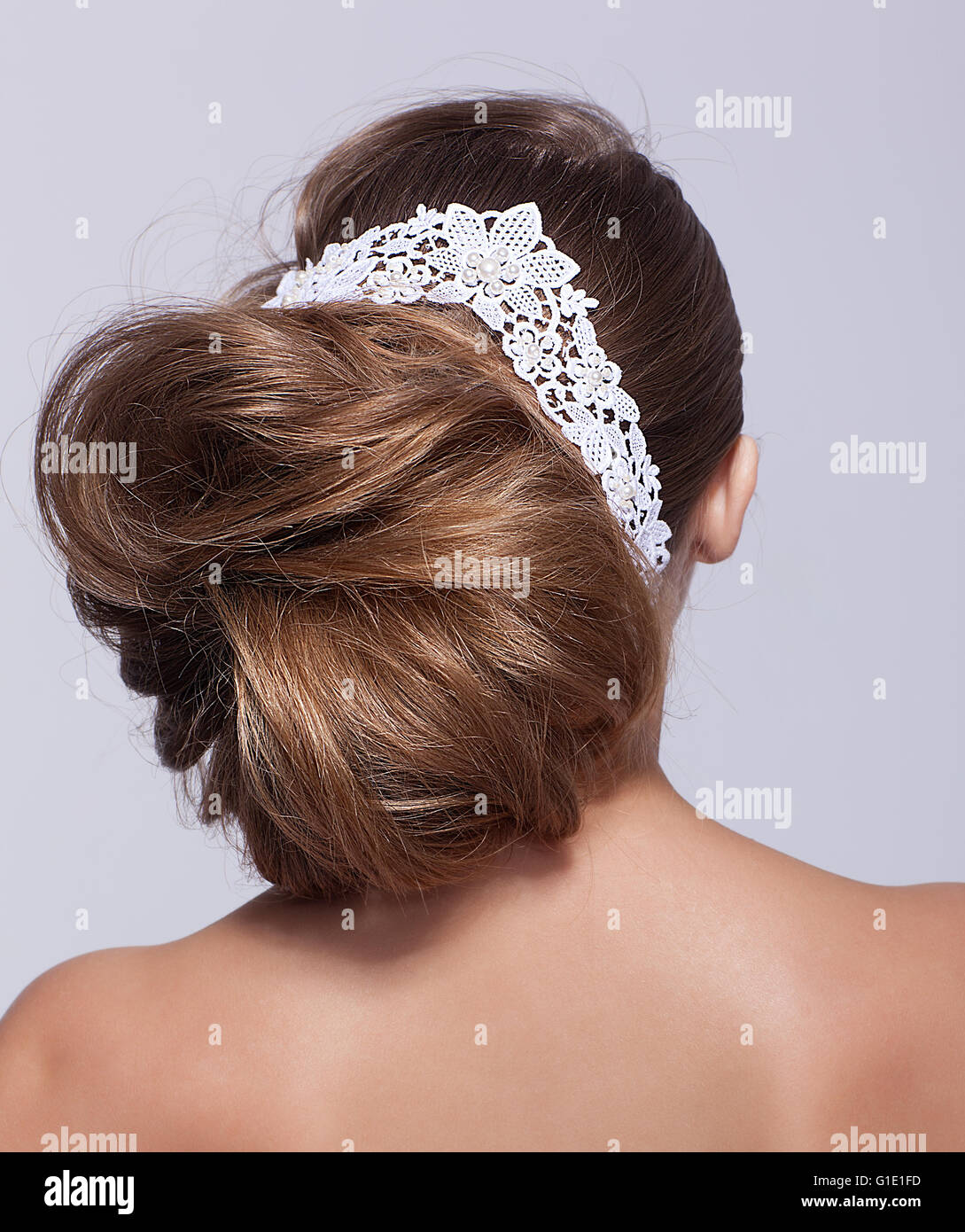 Porträt der schönen jungen Frau auf grauem Hintergrund mit lacy weiße Schleife in die Haare von hinten Stockfoto