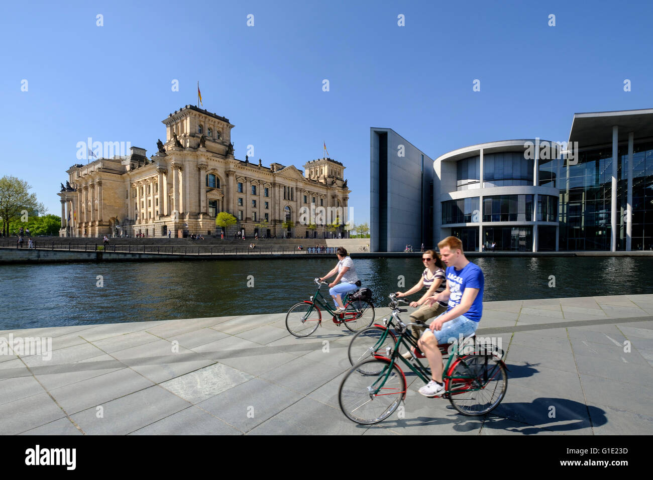 Blick auf den Reichstag Parlamentsgebäude und Touristen auf dem Fahrrad neben Fluss Spree in Berlin Deutschland Stockfoto