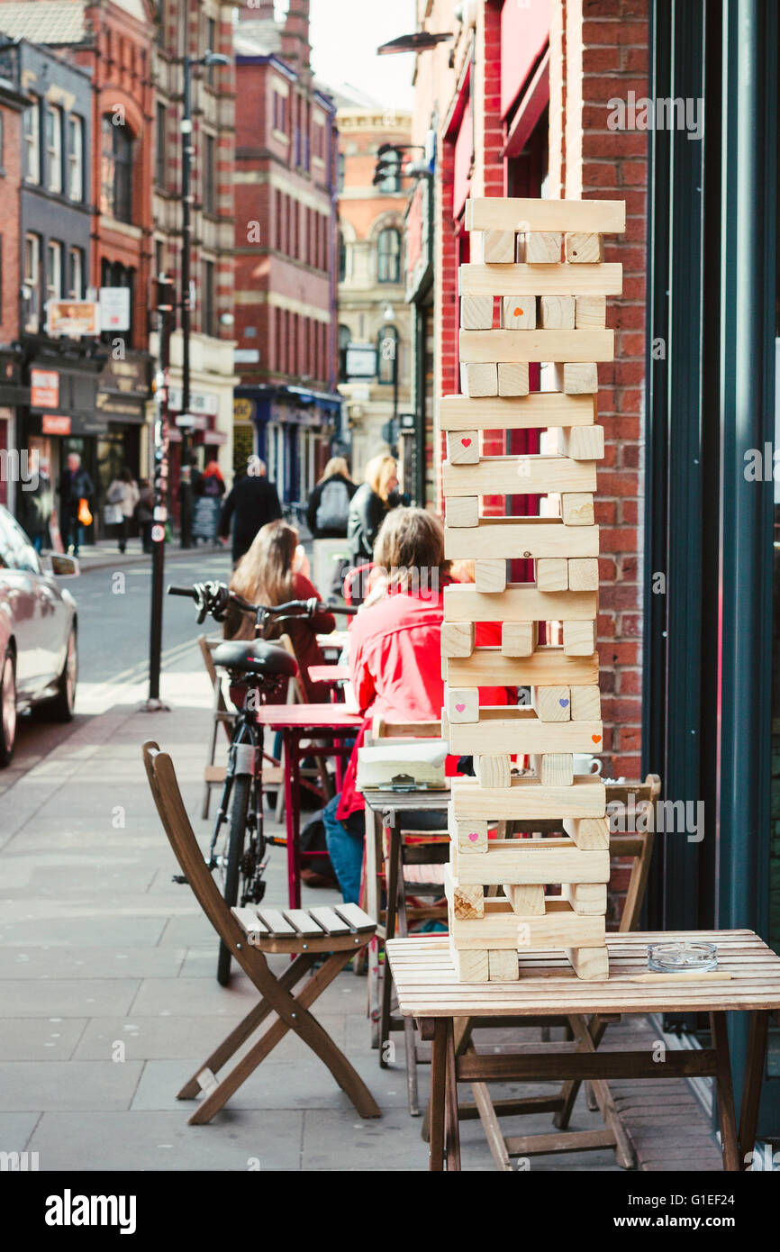 Spiel von Jenga auf einem Tisch auf der Terrasse. Northern Quarter, Manchester Stockfoto