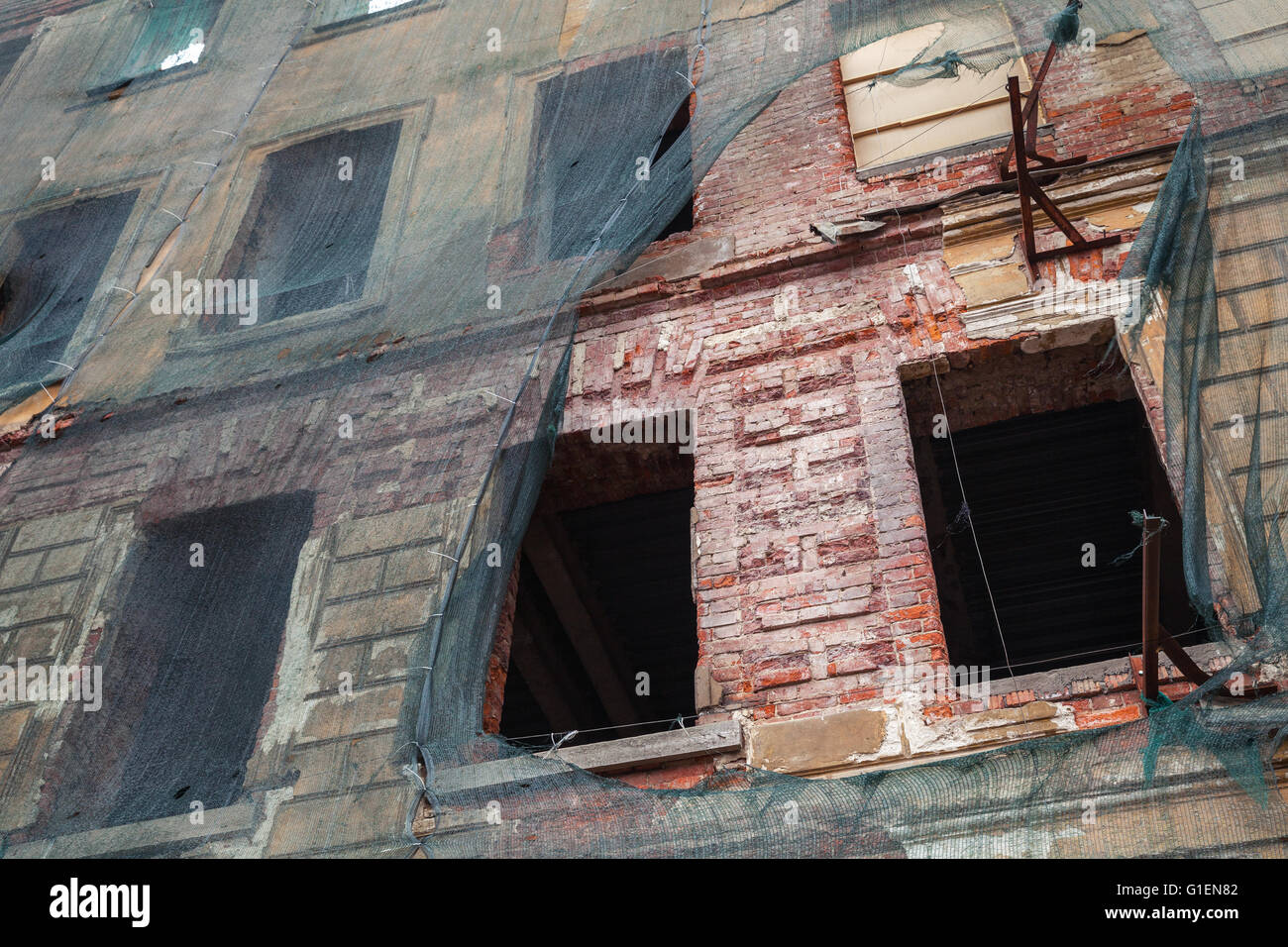 Altes Wohnhaus ist unter Rekonstruktion, roten Backsteinmauer mit grünen Schutz Netz bedeckt Stockfoto