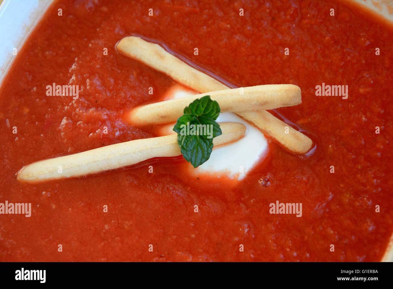 Minze, knackige Grissini und saurer Sahne in leckere Tomatensuppe. Stockfoto