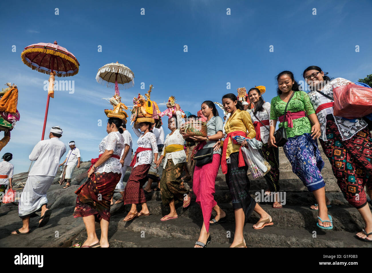 Farbenfrohe Prozession der indonesischen Frauen des Balinese hinduistischen Glaubens tragen religiöse Angebote auf einem Strand in Bali Stockfoto